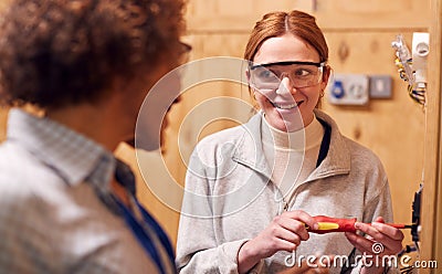 Female Tutor With Trainee Electrician In Workshop Studying For Apprenticeship At College Stock Photo