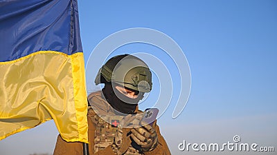 Female ukrainian army soldier using smartphone to read news or messaging with family. Girl in military uniform and Stock Photo