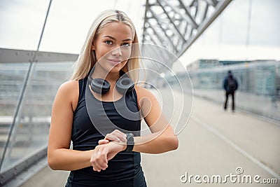 Female Urban Jogger Checking Smartwatch Tracker On Bridge Stock Photo