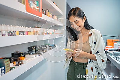 female vape seller looking at her phone while standing beside the shelf Stock Photo