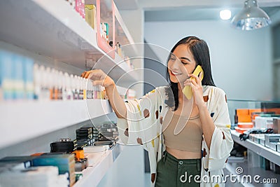 female vape seller observing the liquid stock while calling on phone Stock Photo