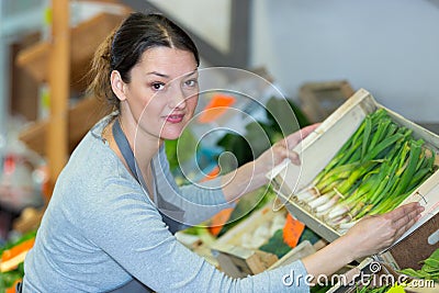 female vegetable vendor taking out leek container Stock Photo
