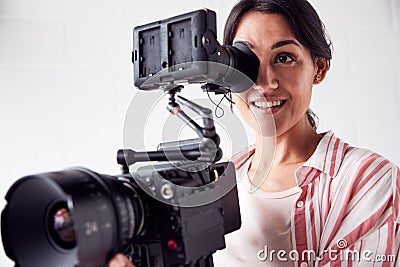 Female Videographer With Video Camera Filming Movie In White Studio Stock Photo