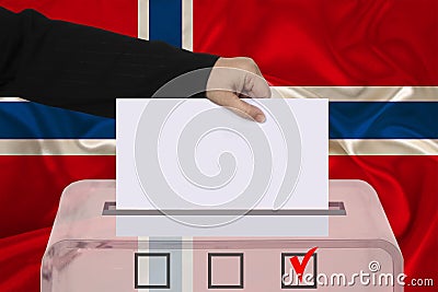 Female voter lowers the ballot in a transparent ballot box against the background of the national flag of Norway, concept of state Stock Photo