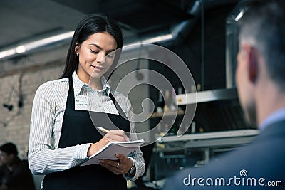 Female waiter in apron writing order Stock Photo