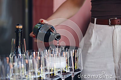 Female waiter pouring sparkling wine to the glass on the bar table, close up without face. Stock Photo