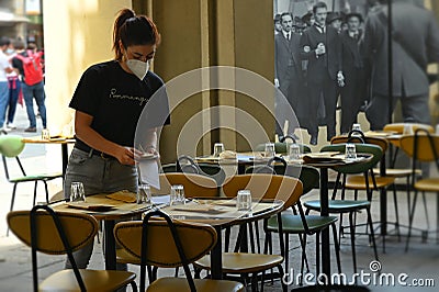 Female waiter setting terrace table of restaurant Editorial Stock Photo