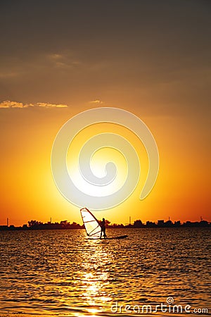 female windsurfer silhouette at lake sunset. Beautiful beach landscape. Summer water sports activities, recreation and Stock Photo