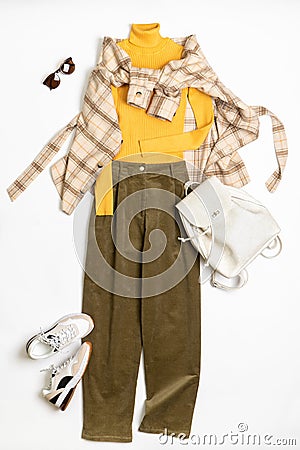 Female winter or autumn stylish clothing set. Plaid checkered shirt, yellow sweater, green corduroy trousers, sneakers and Stock Photo