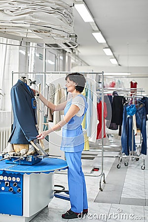 Female worker in Laundry service the process of working on universal automatic equipment for steaming, Ironing and cleaning of Stock Photo