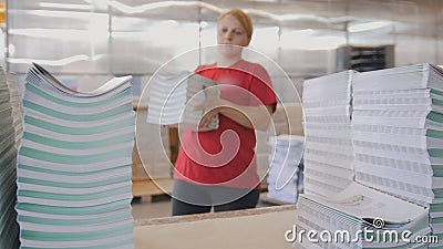 Female worker puts the printed magazines in stacks on the table in the typography Stock Photo