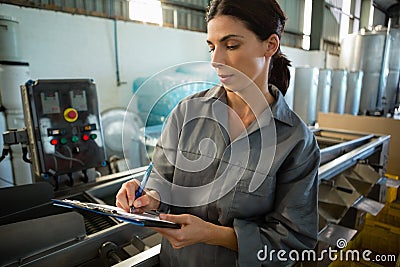 Female worker writing on clipboard in olive factory Stock Photo