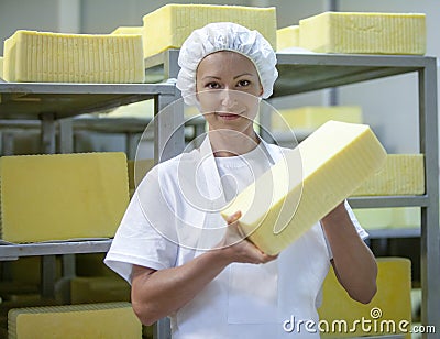 Female worker on yellow cheese production line in an industrial Stock Photo