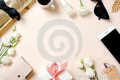 Female workspace with smartphone, roses flowers, golden accessories, gift box, glasses, coffee cup. Flat lay women`s office desk. Stock Photo