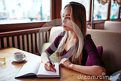 Female writing in notebook in restaurant. Stock Photo