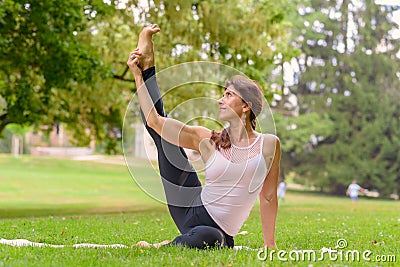 Female yoga artist doing leg exercises in meadow Stock Photo