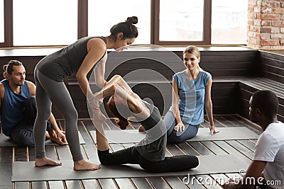 Female yoga instructor helping woman doing exercise at group tra Stock Photo