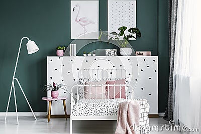 Feminine bedroom interior with a bed, bedside table, lamp, plant Stock Photo