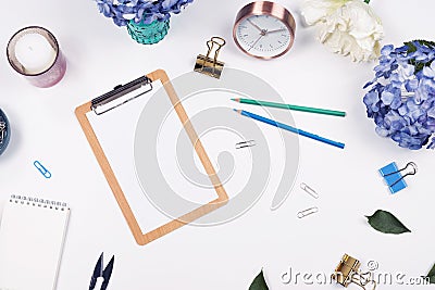 Feminine desk workspace frame with beauty arrangement of bouquet hydrangeas, clipboard, coffee cup, clips, clock, pencil and candl Stock Photo