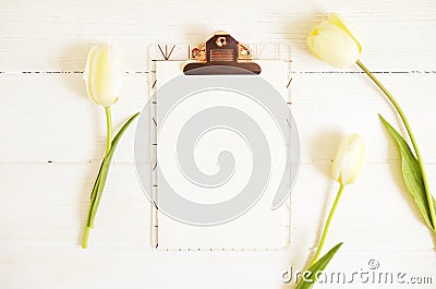 Feminine desktop composition with blank sheet clipboard & white tulips on wooden texture table background, copy space for text. Wo Stock Photo