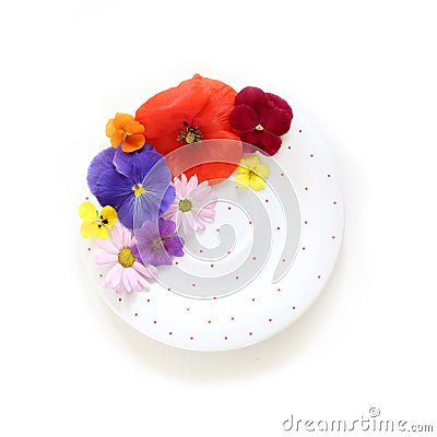 Feminine floral scene. Composition of edible wild and garden flowers, polka dot porcelain plate on white background Stock Photo