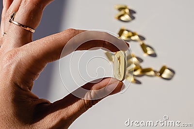 Feminine hand holding yellow capsule close up Stock Photo