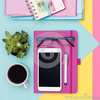 Office Desk Working Space Flat Lay. Top view photo of workspace with smartphone, coffee, notepad and woman fashion magazines. Stock Photo