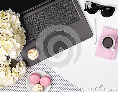 Feminine office table desk with laptop, notebook, pen, sunglasses, flowers and macaroon Stock Photo