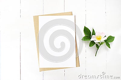 Feminine wedding stationery, floral desktop mock-up scene. Blank greeting card, craft envelope and blooming wild rose Stock Photo