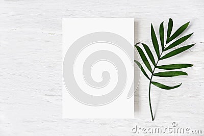 Feminine wedding stationery mock-up, desk scene. Blank greeting card and green palm leaf on white shabby table Stock Photo