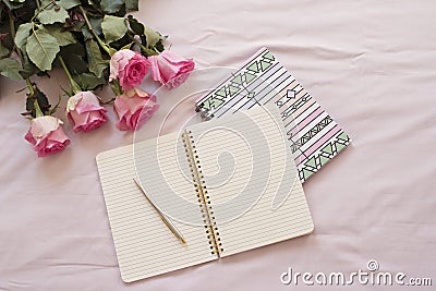 Feminine workplace concept. Freelance fashion comfortable femininity workspace in flat lay style with open notebook, pink rose flo Stock Photo