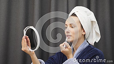 Femme qui applique du rouge à lèvres et qui regarde le miroir Une jolie femme charmante en peignoir peint les lèvres à la maison banque de vidéos Femme qui applique du rouge à lèvres et qui regarde le miroir Une jolie femme charmante en peignoir peint les lèvres à la maison banque de vidéos