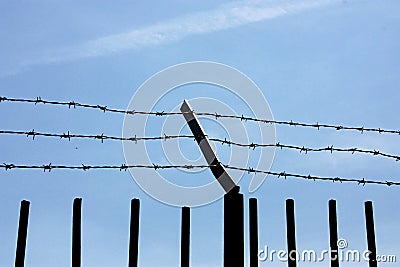 fence with barbed wire against the blue sky. Symbol of freedom of imprisonment Stock Photo