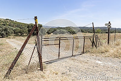 A fence with gate on a country road in Almaden de la Plata Stock Photo