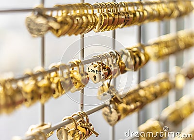 Golden love padlocks locked on a fence with a handwriting love word. Editorial Stock Photo