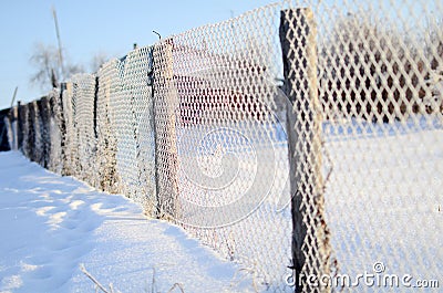 A fence of mesh netting covered with frost in a Sunny day Stock Photo