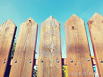 Fence palisade fence on blue sky background. Pointed logs old wood texture. Stock Photo