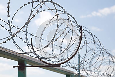 Fence with razor barbed wire protection against blue sky background. Dictatorship and tyranny concept Stock Photo