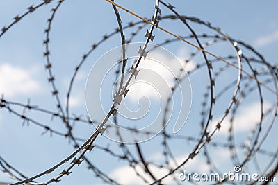 Fence with razor barbed wire protection against blue sky background. Dictatorship and tyranny concept Stock Photo