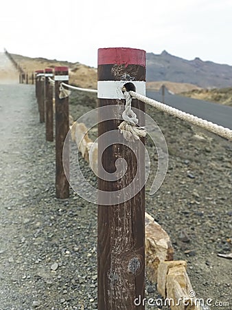 Fence of round wooden posts attached with a rope to delimit the path. High mountain trail marking with Wooden fence posts. Stock Photo