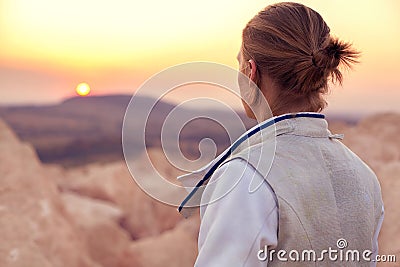 Fencer man on the rocky background and looking forward to the sun goes down Stock Photo