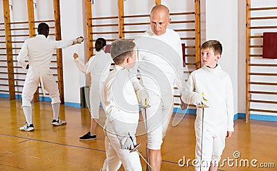 Fencing instructor with young fencers in training room Stock Photo