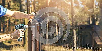 Fencing - worker installing metal wire mesh fence panel Stock Photo