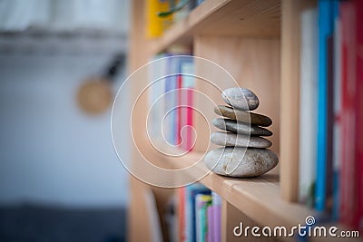 Feng Shui: Stone cairn in a book shelf in the living room, balance and relaxation Stock Photo