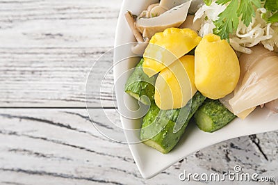 Fermented food in a plate on a white textural wooden table. Cucumbers, zucchini, garlic, marinade, tomatoes, cabbage, ramson, pars Stock Photo