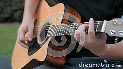 Fermeture d'un jeune homme jouant de la guitare acoustique à l'extérieur Mains d'un homme jouant les cordes de laiton d'une guita clips vidéos Fermeture d'un jeune homme jouant de la guitare acoustique à l'extérieur Mains d'un homme jouant les cordes de laiton d'une guita clips vidéos