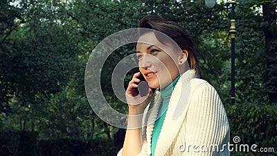 Fermez-vous vers le haut de la femelle avec le téléphone portable parlant et de sourire de cheveux courts en parc banque de vidéos Fermez-vous vers le haut de la femelle avec le téléphone portable parlant et de sourire de cheveux courts en parc banque de vidéos