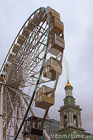 Ferris wheel in historical part of Kyiv. The bell tower of the Former Greek Monastery at the background Stock Photo