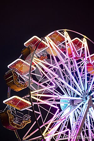 Ferris wheel at night, illuminated by colorful neon lights. Detail, vertical Stock Photo