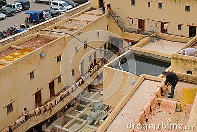 Fes, Morocco - male worker hangs animal hides on a balcony to dry under the sun at Chouara Tannery in Fes el Bali. Editorial Stock Photo